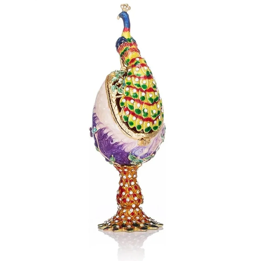 Huevo ornamental con una figura de pavo real de colores sobre un pedestal.