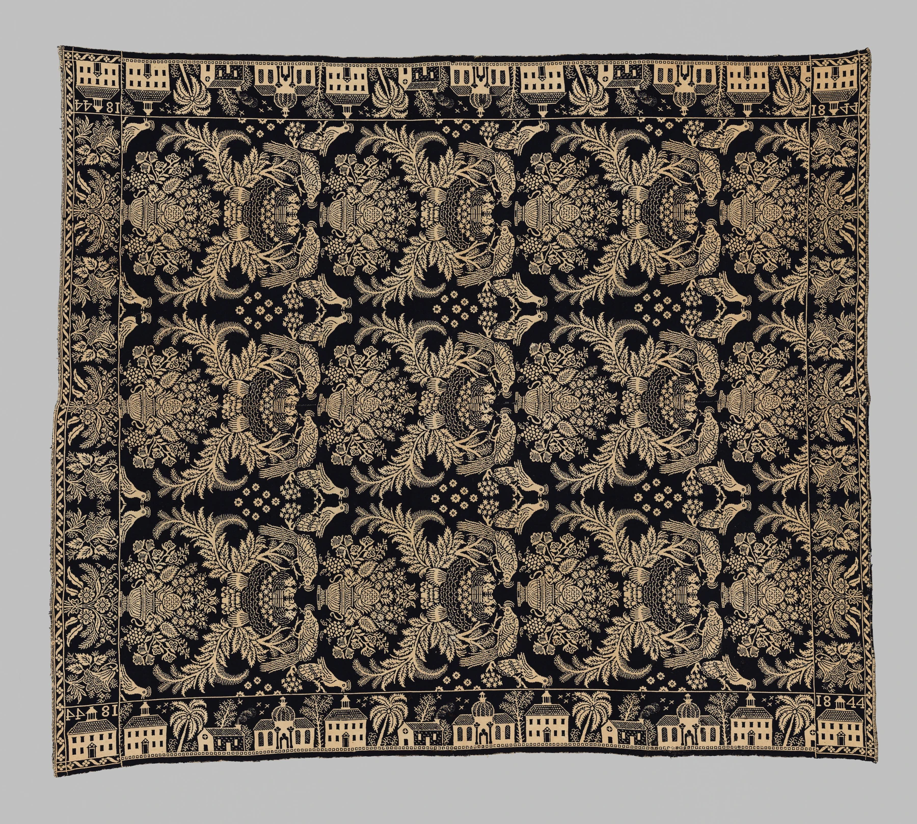 Colcha histórica de 1844 con pavos reales y motivos vegetales tejidos en azul oscuro y crudo.