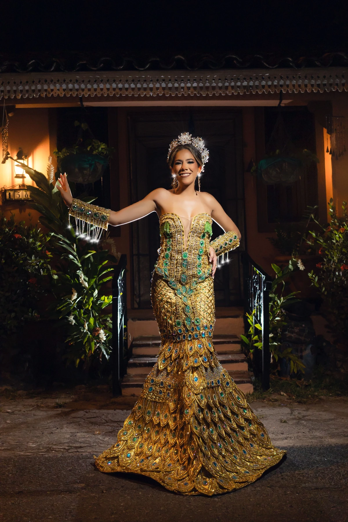 Vestido largo dorado con motivos de plumas y ocelos verdes y azules en la falda.